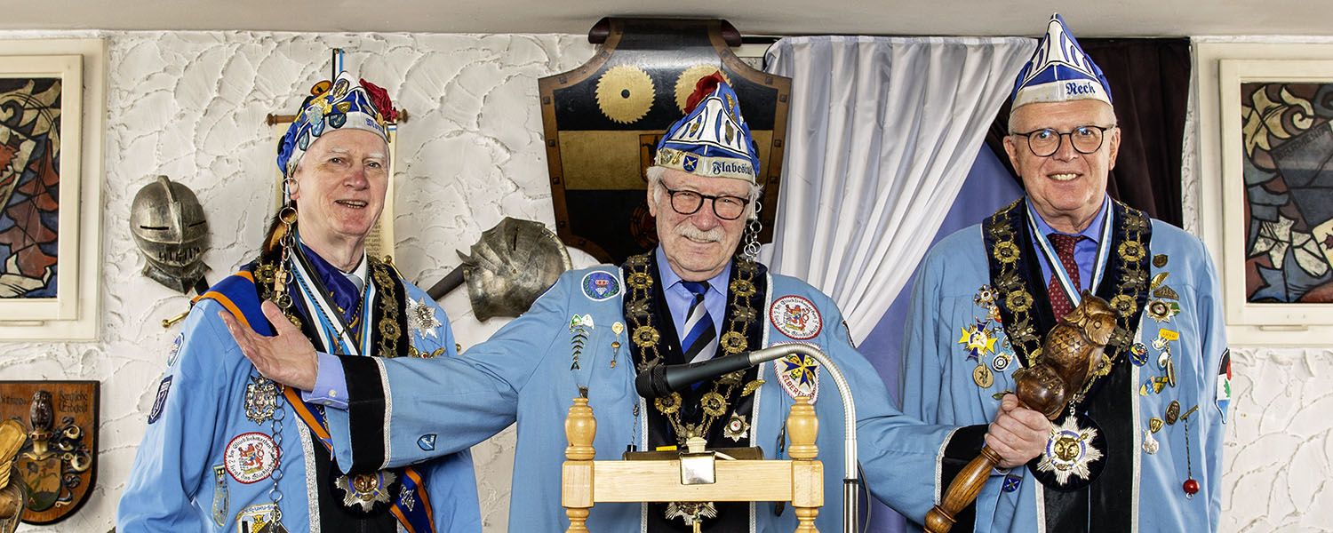 Die Oberschlaraffen heißen Euch willkommen Drei Personen in traditionellen blauen Outfits begrüßen Gäste herzlich